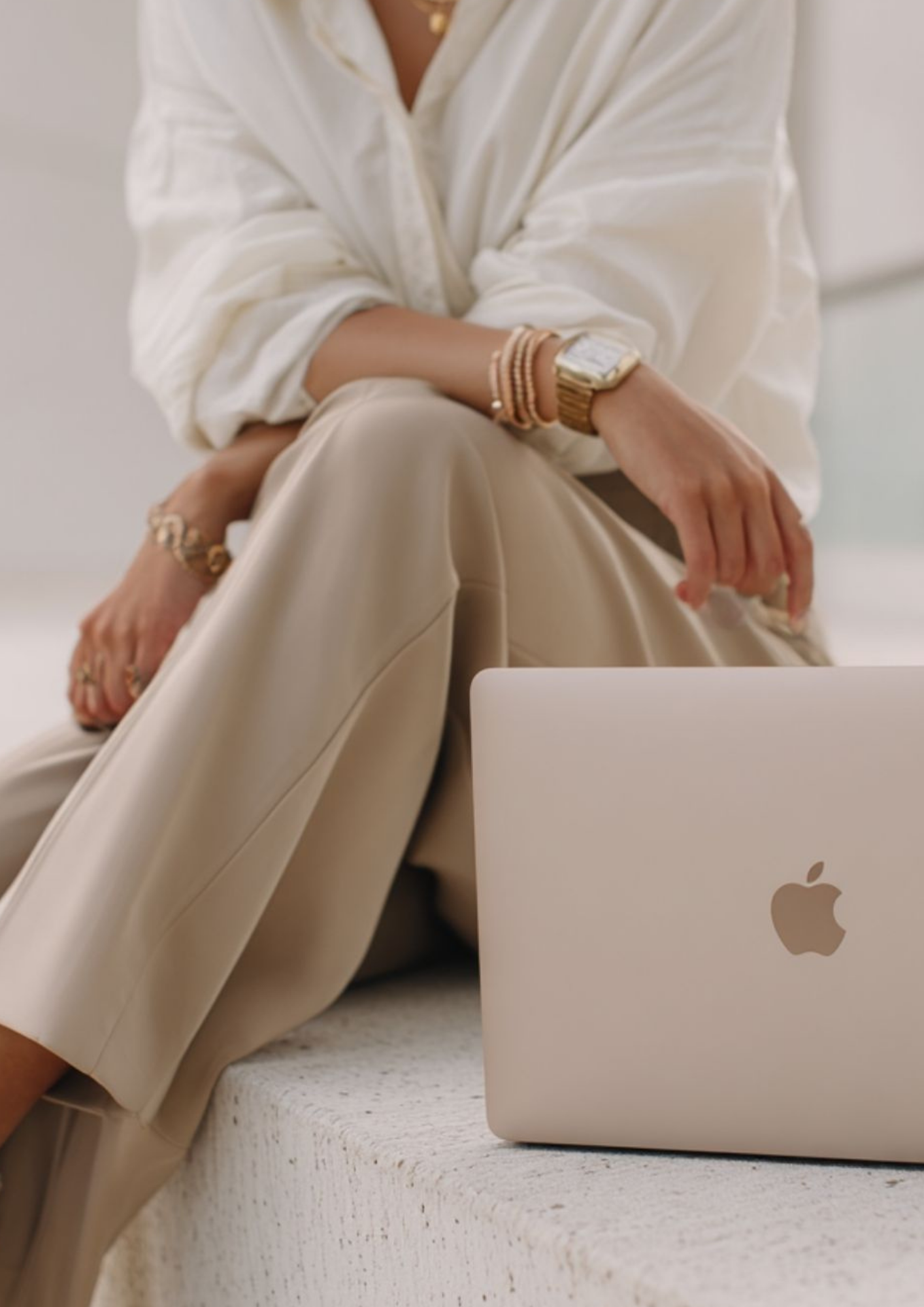 Femme élégante assise avec un MacBook représentant une formatrice esthétique indépendante